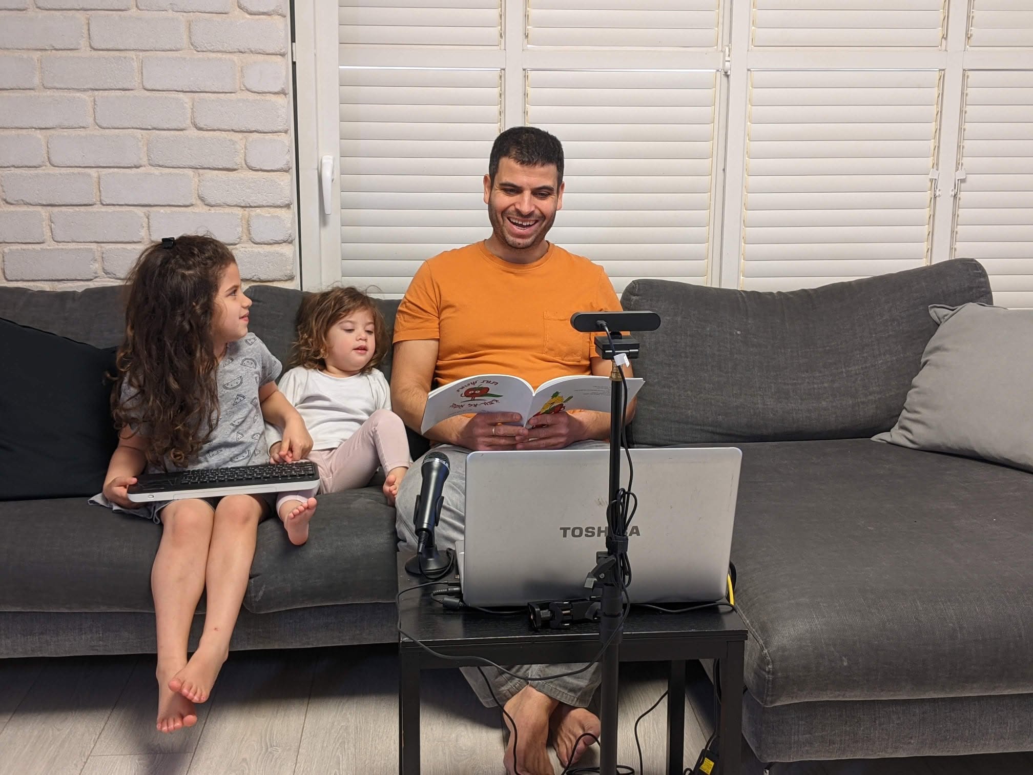 שאול בן חור מקריא את הספר בסלון לצד בנותיו